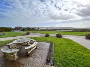 a picnic table and two benches on a wooden deck at Fern Lodge - Uk51604 in Peel