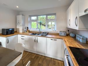 a kitchen with white cabinets and a sink at Fern Lodge - Uk51604 in Peel