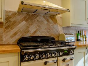 a stove top oven in a kitchen with a hood at Honeycott in Crickhowell