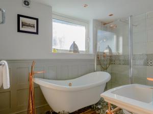 a white bath tub in a bathroom with a window at Honeycott in Crickhowell