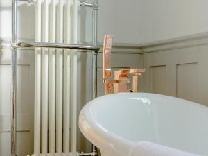 a bathroom with a white sink and a radiator at Honeycott in Crickhowell