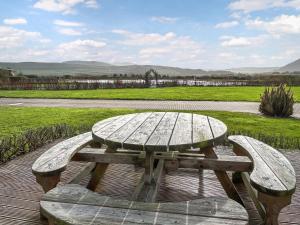 a wooden picnic table and bench with a view of a field at Wisteria Lodge - Uk51605 in Peel