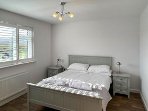 a white bedroom with a bed and a window at Wisteria Lodge - Uk51605 in Peel