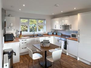 a kitchen with white cabinets and a table and chairs at Wisteria Lodge - Uk51605 in Peel +7 photos