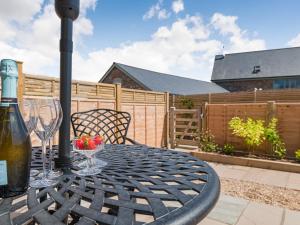 a patio table with wine glasses and a bottle of wine at The Stables - Cottage in Raglan