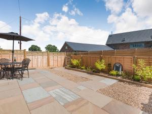 a patio with a table and an umbrella and a fence at The Stables - Cottage in Raglan