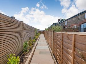 a wooden fence with a sidewalk and plants at The Stables - Cottage in Raglan +21 photos