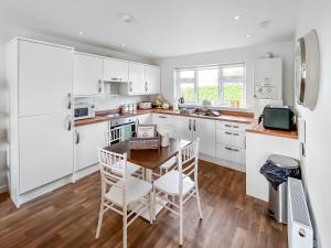 a kitchen with white cabinets and a table and chairs at Primrose Lodge - Uk51602 in Peel