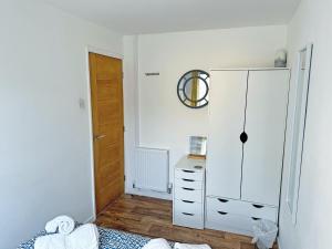 a bedroom with a white cabinet and a bed at Beach Cottage in Benllech