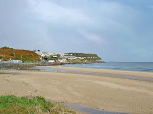 a beach with the ocean and a town in the background at Beach Cottage in Benllech