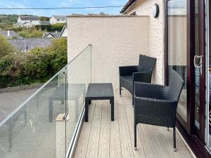 two chairs and a glass table on a balcony at Beach Cottage in Benllech +12 photos