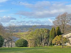 a view of a field with trees and a house at Spruce Cottage in Tywardreath