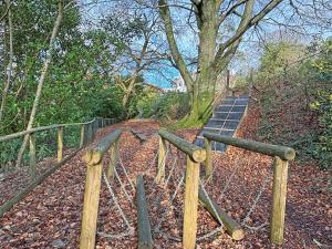 a wooden fence next to a path in the woods at Spruce Cottage in Tywardreath +10 photos