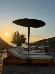 a group of lounge chairs with an umbrella on a beach at Sun Holiday Kea Private Pool Sea View in Pisses