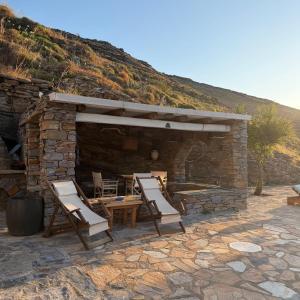 a group of chairs and a table and a stone building at Sun Holiday Kea Private Pool Sea View in Pisses +15 photos