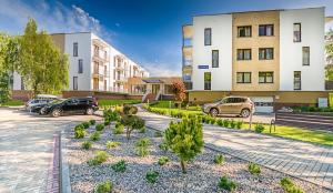 a parking lot with cars parked in front of buildings at Apartament Darłówko in Darlowko