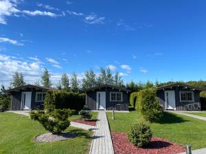 a row of cottages on a lawn with bushes at Nameliai TRES in Bernotiškė +24 photos