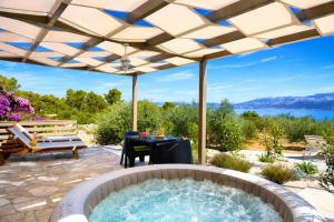 a hot tub in a patio with a table and a bench at Olive Garden Home with Jacuzzi and Privacy in Mirce