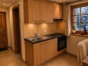 a kitchen with wooden cabinets and a sink and a window at Chalet Nunavut, Ski in - Ski out with Complimentary Spa Access in Zermatt