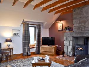 a living room with a fireplace and a tv at Buchanan's Bothy in Glencarse