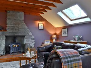 a living room with leather furniture and a stone fireplace at Buchanan's Bothy in Glencarse +8 photos