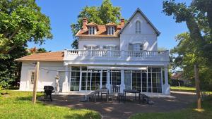 a large white house with tables and chairs in front of it at Grandiflora in Saint-Julien-en-Born