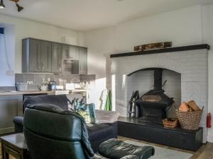 a living room with a fireplace with a couch and a chair at Cowar Bothy in Dalbeattie