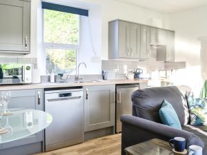 a kitchen with white cabinets and a couch and a table at Cowar Bothy in Dalbeattie