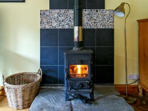 a wood stove in a room with a basket at The Barn - S4593 in Lochearnhead