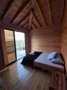 a bed in a wooden room with a large window at Cabaña del Sol in Medellín