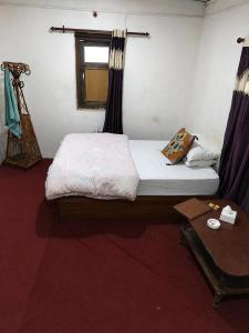 a bedroom with a bed and a window and a table at Newari chulo ghar in Bhaktapur +7 photos