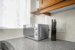 a microwave on a counter in a kitchen at Modern 2 BR ground floor apartment with parking and garden in Belvedere