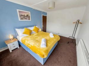 a blue bedroom with a bed with a yellow blanket at Modern 2 BR ground floor apartment with parking and garden in Belvedere