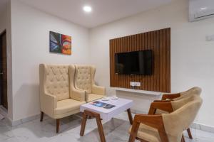 a living room with two chairs and a tv at ABI RESIDENCY Hitech City in Hyderabad +32 photos