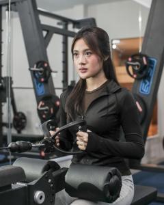a woman sitting on a exercise bike in a gym at Gosyen Azana Hotel Salatiga in Salatiga