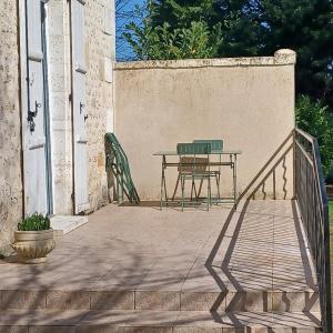 a table and a bench on a patio at Escale en sud Charente in Chavenat