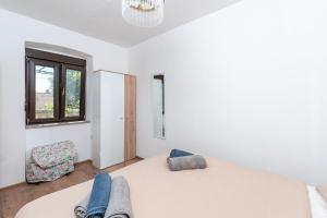 a white bedroom with a bed and a window at Apartman Miriam in Opatija