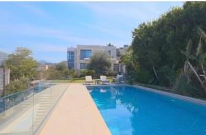 a large blue swimming pool in front of a building at Gümüşlük Infinity Villa Seaview, Pool & Sauna in Bodrum City