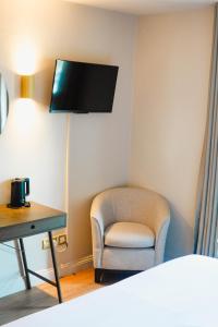 a room with a chair and a desk and a tv at The Village Hotel Douglas in Cork