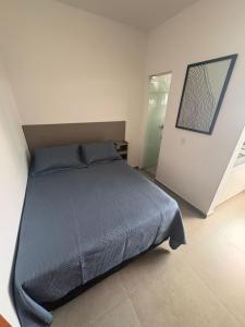 a bedroom with a bed with a blue comforter at Smart Studio Lavras in Lavras