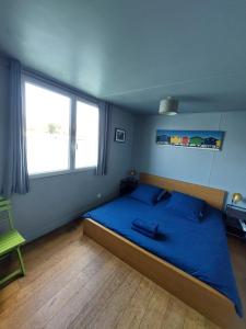 a bedroom with a bed with blue sheets and a window at Chambres sur Seine Megalight2 in Sèvres