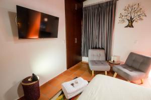 a bedroom with a bed and a chair and a television at Casa Amarilla in San Gil