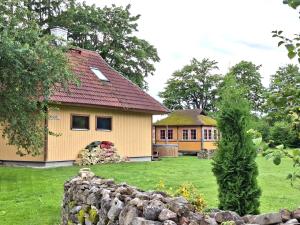 a yellow house with a stone wall in a yard at Sika Holiday Houses in Hellamaa