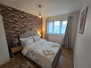 a bedroom with a bed and a brick wall at Relax Stay 2 Bedroom in Theale