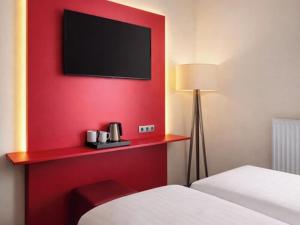 a hotel room with a red wall with a tv at DORMERO JeHo Graz Airport in Feldkirchen bei Graz +8 photos