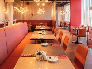 a restaurant with long tables and chairs and chandeliers at DORMERO JeHo Graz Airport in Feldkirchen bei Graz