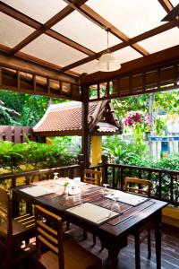 a wooden table with chairs and an umbrella on a patio at Lamphu Tree House Boutique Hotel in Bangkok