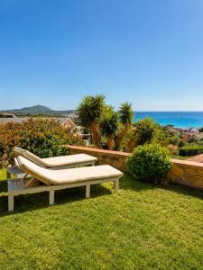 a bench sitting on the grass near the ocean at Villasimius Il patio sul porto in Villasimius