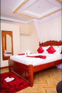 a bedroom with a bed with red pillows and a mirror at Hillpark Hotel in Eldoret
