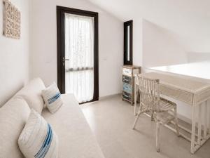 a white living room with a couch and a desk at Villasimius Il patio sul porto in Villasimius +11 photos